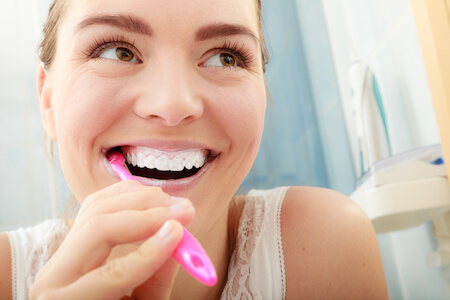 Woman brushing teeth and smiling